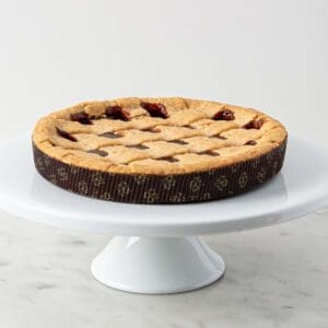 A pie sitting on top of a white cake plate.